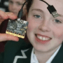 A child smiling and holding up a Raspberry Pi.