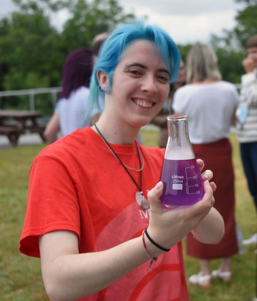 A young woman at Agile on the beach youth holding a drink in a beaker.