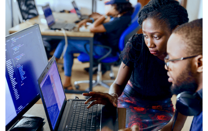 A woman and man both looking at two screens together - tech academy.