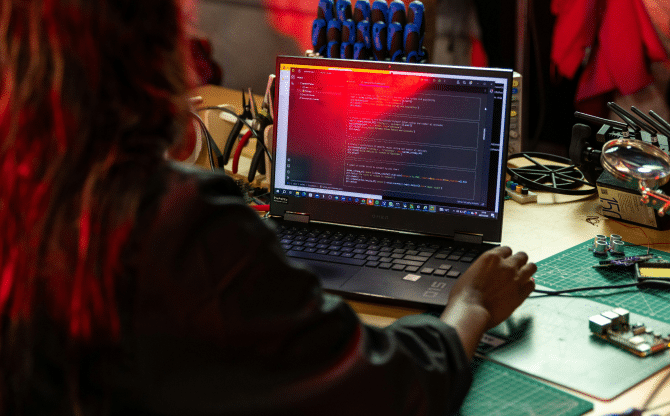 The back of a womans head as she's coding on her computer.