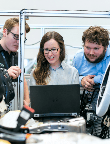 Two teachers helping a young woman learn tech.