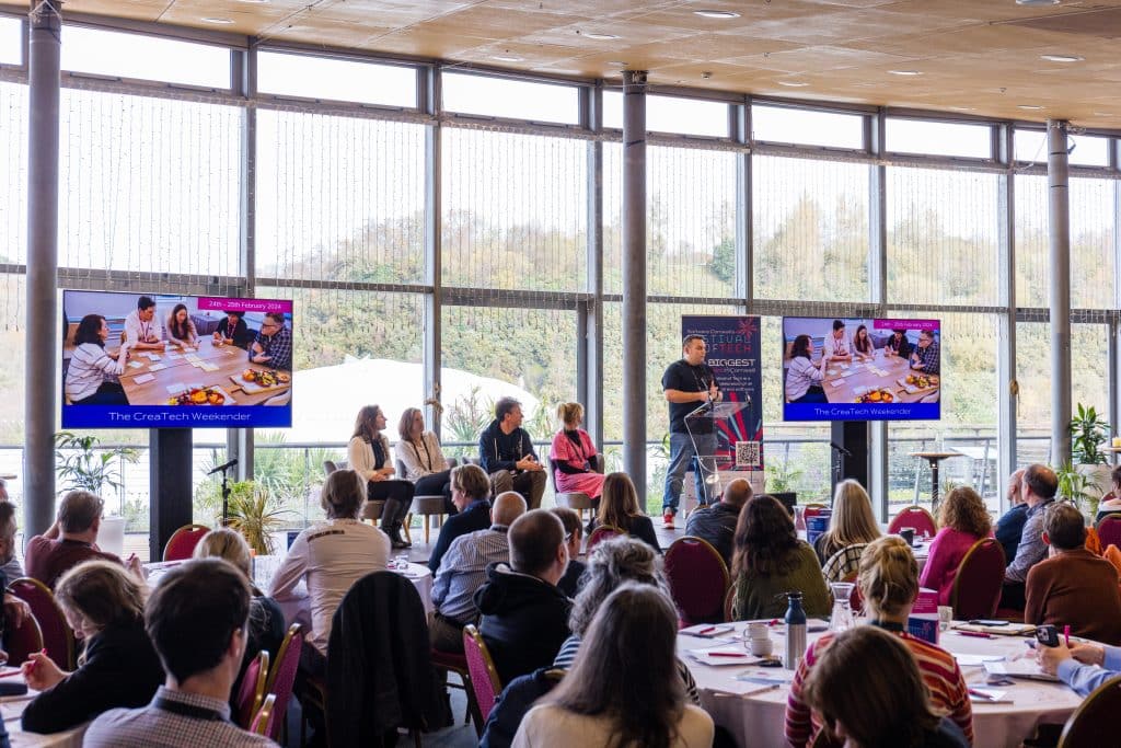 Audience seated at round tables looking at the stage during Tech Corwall's Festival of Tech.